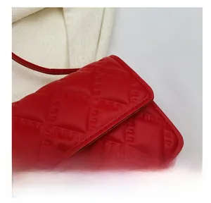 Close-up of red quilted leather texture and gold hardware on a crossbody bag