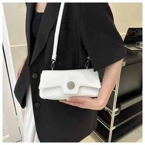 Close-up of minimalist white baguette bag with matte round metal snap on black blazer