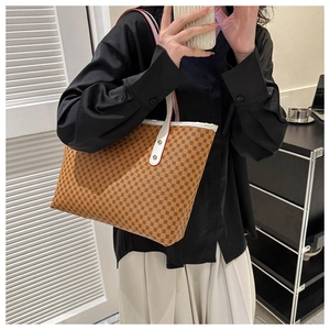 Close-up of brown patterned tote bag with contrast stitching and rivet details