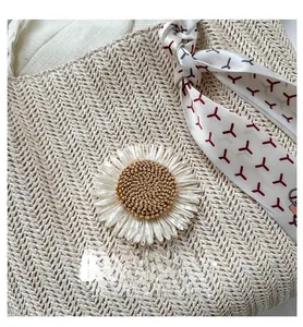 Détail du sac en paille tressée avec marguerite 3D et foulard en soie à motif géométrique
