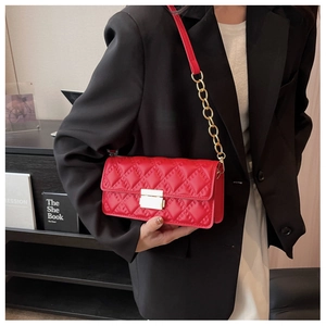 Detail of red quilted cross-body bag featuring a gold metal buckle and elegant chain strap