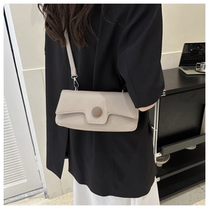 Detail of beige rectangular minimalist crossbody bag styled with a professional suit