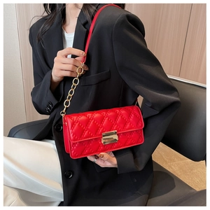Detail of red quilted crossbody bag with gold chain strap worn with a black blazer