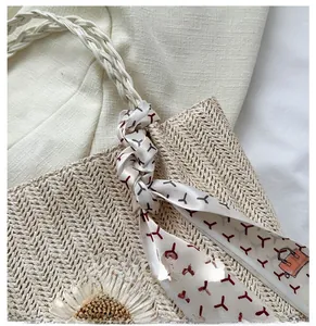 Détail d'un sac en paille tressée avec fleur de marguerite et foulard en soie décoratif