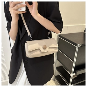 Model wearing a minimalist off-white baguette bag with a round buckle over a blazer
