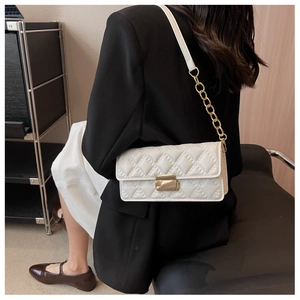 Detailed view of white quilted chain bag with gold lock on female model