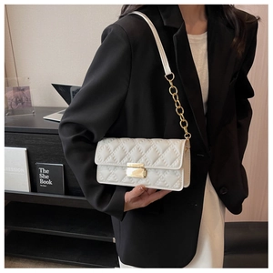 Close-up of white quilted crossbody bag with gold chain strap and metal lock detail