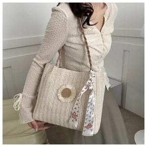 Détail d'un grand sac en paille beige avec marguerite et foulard élégant en soie géométrique