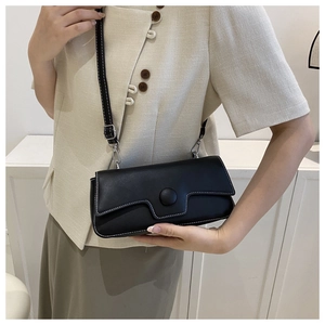 Close-up of black rectangular crossbody bag with contrast white stitching and silver hardware