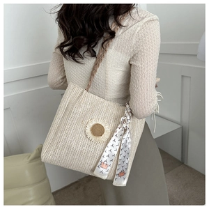 Détail du sac cabas en paille tissée avec breloque tournesol et foulard en soie
