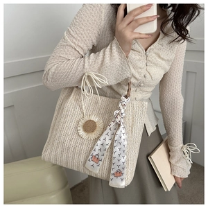 Détail du sac cabas en paille avec breloque tournesol, foulard en soie et cordon
