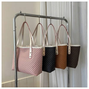 Close-up of four colored checkered tote bags on a display rack with gold rivet details