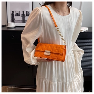 Detail of bright orange quilted crossbody bag featuring silver lock and chain strap