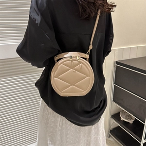 Beige round quilted crossbody bag with top handle and adjustable strap for women