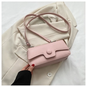 Detail of light pink leather crossbody bag featuring a round buckle on soft blazer