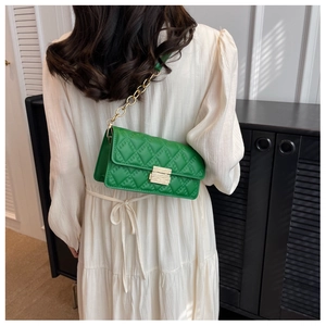 Detail of green quilted crossbody bag with gold chain strap and metallic turn-lock closure