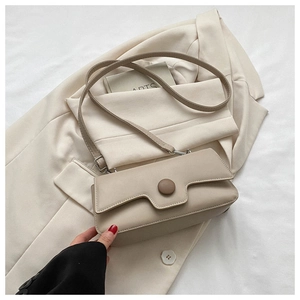Macro detail of beige crossbody bag featuring large circular buckle and soft texture