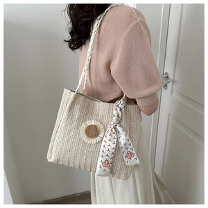 Détail du sac cabas en paille avec fleur blanche et foulard en soie à motifs géométriques
