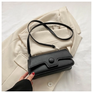 Detail of black faux leather bag with white contrast stitching and round buckle decorative flap