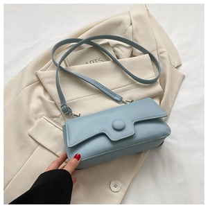 Detail of light blue leather crossbody bag with round buckle on neutral background