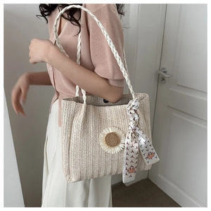 Détail du sac cabas en paille tissée avec fleur de tournesol et foulard élégant