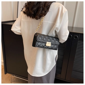 Detailed view of black quilted crossbody bag featuring golden chain and metal lock