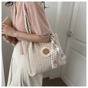 Détail d'un sac cabas en paille tressée avec marguerites et accessoire foulard en soie