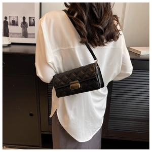 Detail of black quilted shoulder bag featuring classic diamond stitching and gold buckle