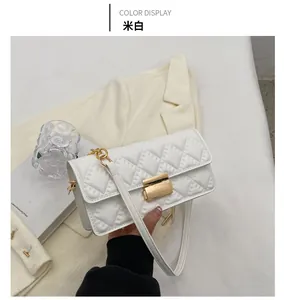 Close-up of off-white quilted crossbody bag with gold metal clasp on white blazer