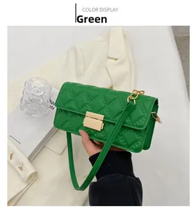 Detail of green quilted shoulder bag featuring gold rectangular metal clasp and chain