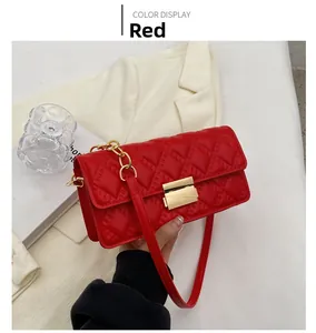 Detail of red quilted crossbody bag featuring a gold clasp and elegant chain strap