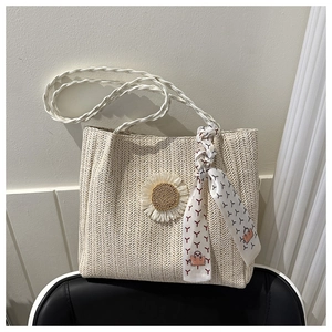 Détail du sac fourre-tout en paille beige avec breloque tournesol et foulard en soie