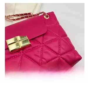 Close-up of quilted rhombic stitching and gold lock on rose red crossbody bag