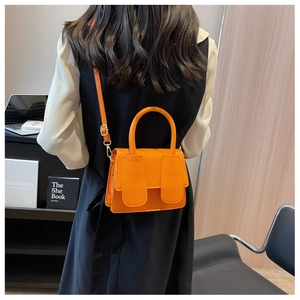 Oranje crossbodytas van generfd leer gedragen door een model in een moderne kamer