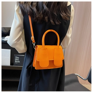 Detail van de oranje crossbodytas met lychee-textuur getoond in kantooromgeving