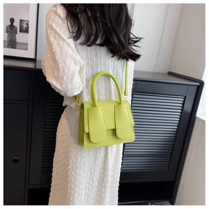 Lichtgroene leren crossbodytas met lycheestructuur en brede riempjes op de flap