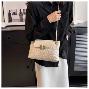 Close-up of quilted cream leather shoulder bag featuring a gold twist-lock and chain strap