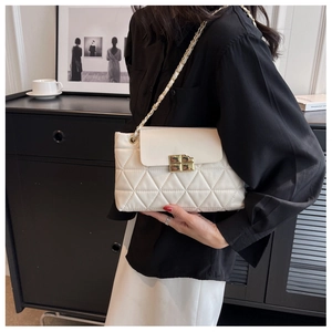 Detailed view of white quilted crossbody bag with gold chain strap and twist lock