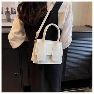Detail van een witte mini-tas van generfd leer met gouden hardware en schouderriem