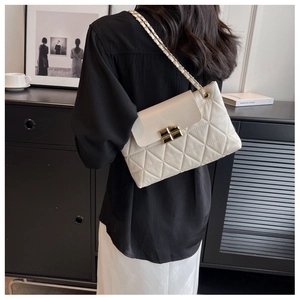 Close-up of white quilted chain bag with gold metal lock showing shoulder strap detail