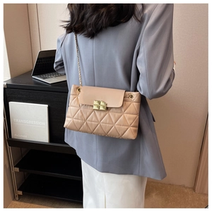 Detail view of beige quilted bag featuring a golden twist lock and chain strap