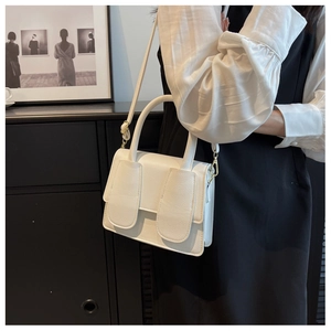 Detail van witte litchi lederen handtas met goudkleurige hardware en verstelbare riem