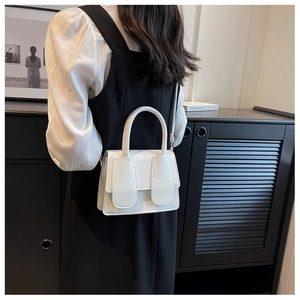 Detailweergave van een witte crossbodytas van generfd leer gedragen door een model