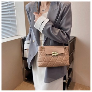 Close-up of beige quilted chain bag with gold twist lock on a fashion model
