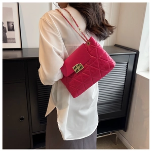 Deep pink quilted shoulder bag with gold cross lock and leather chain strap on model