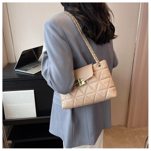 Close-up of beige quilted crossbody bag with gold chain strap and metal turn-lock