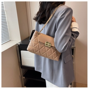 Detail of beige quilted shoulder bag featuring gold chain strap and metal turn-lock closure