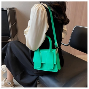 Detail van een felgroene crossbodytas van leer met konijnenoren en een verstelbare riem
