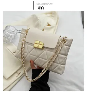 Detail of off-white quilted crossbody bag featuring a golden chocolate-style lock
