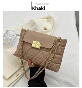 Detail of khaki quilted bag featuring a golden geometric lock and metal chain strap